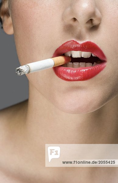 A woman wearing red lipstick and smoking a cigarette - royal.
