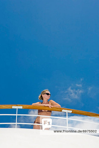 Woman Wearing Bikini Leaning On Railing Of Cruise Ship