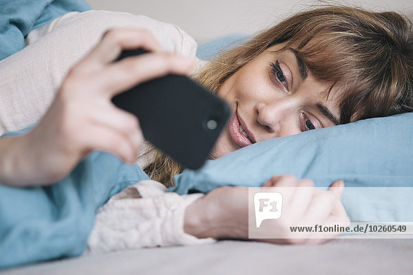 Handy,junge Frau,junge Frauen,benutzen,Entspannung,Bett,Kurznachricht