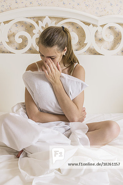 sitzend,junge Frau,junge Frauen,umarmen,Depression,Bett,Kopfkissen