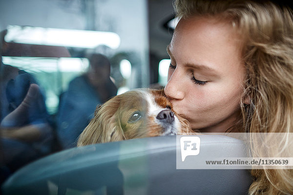 Junge Frau küsst einen Hund im Auto