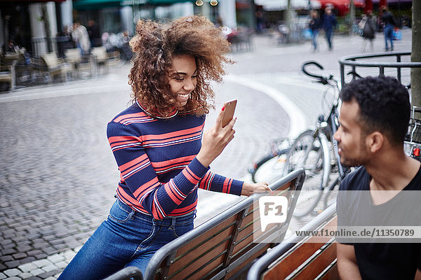 Junge Frau macht ein Handyfoto ihres Freundes