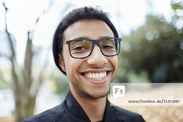 Portrait eines lächelnden jungen Mannes mit Brille im Freien