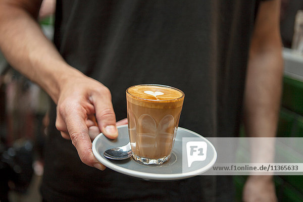 Gefrorener Schuss von Barista mit Glas Kaffee im Cafe