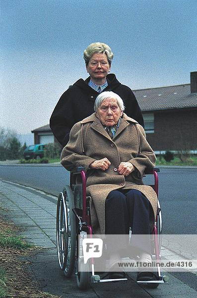 Frau Druck der älteren Frau auf Rollstuhl  Deutschland