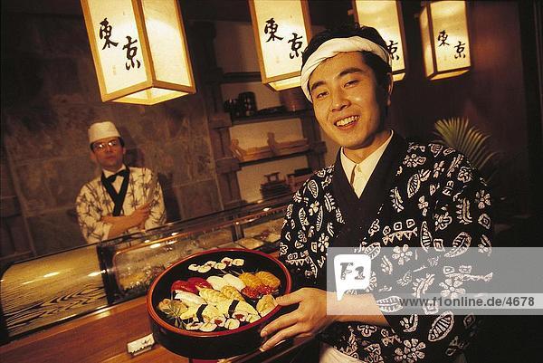 Portrait des japanischen Kellner mit Sushi in einer Kasserolle  Deutschland