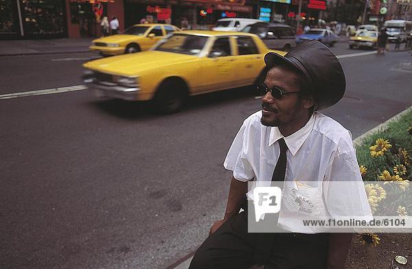 Mann sitzen am Straßenrand  Times Square in New York City  New York State  USA