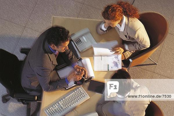 High angle view of two businessmen and a businesswoman discussing in an office