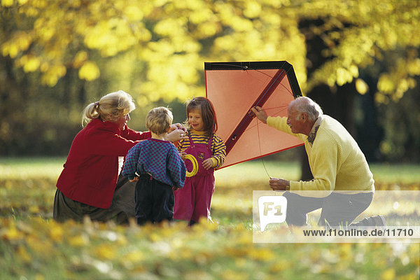 Headline: älteres Paar spielen mit ihren Enkelkindern in einem park