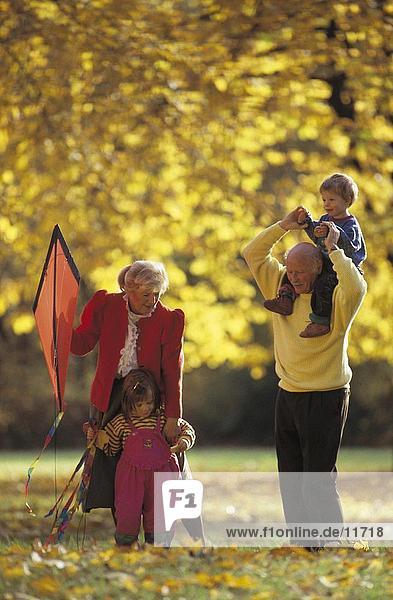 älteres Paar spielen mit ihren Enkelkindern in einem park