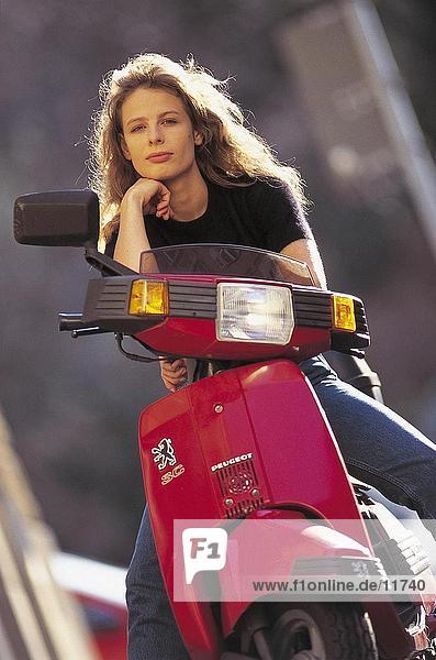 Young woman sitting on a motor scooter