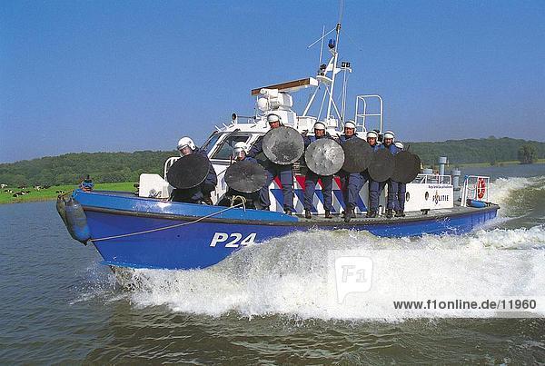 Policemen holding shields on boat in river  Netherlands