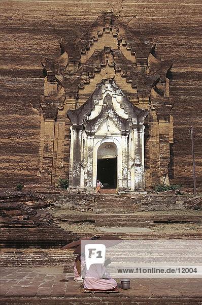 Buddhistische Mönche sitzend mit Sonnenschirmen am Eingang des Tempels  Mingun Tempel  Myanmar