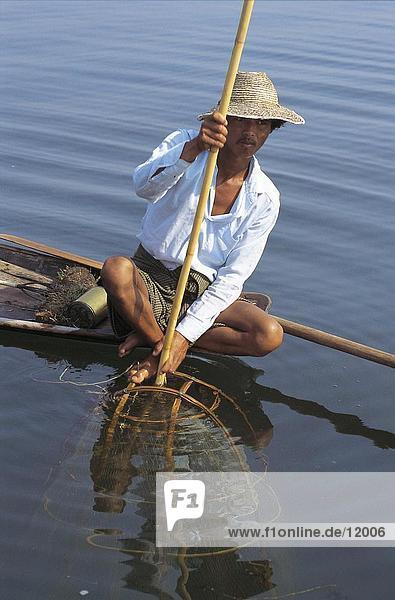 Fisherman fishing with wooden net in lake  Inle Lake  Myanmar