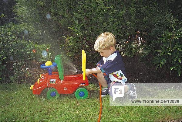 Seitenansicht Junge spielt in Garten mit Gartenschlauch