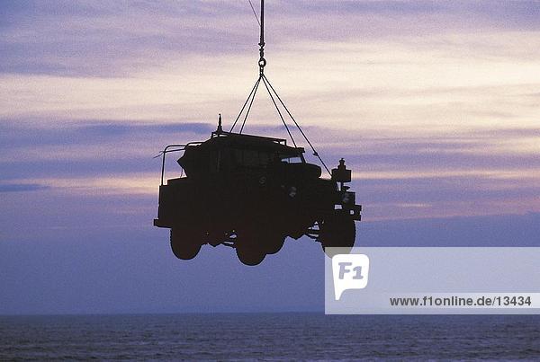 Silhouette of hanging military car against cloudy sky