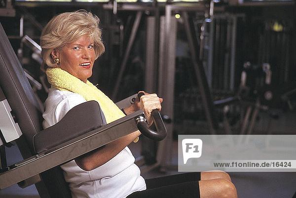 Portrait of mature woman exercising and smiling in gym