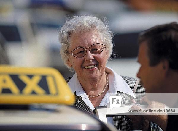 Senior woman hiring a taxi at taxi station