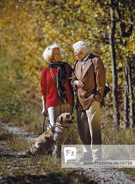 Senior couple standing with dog in park