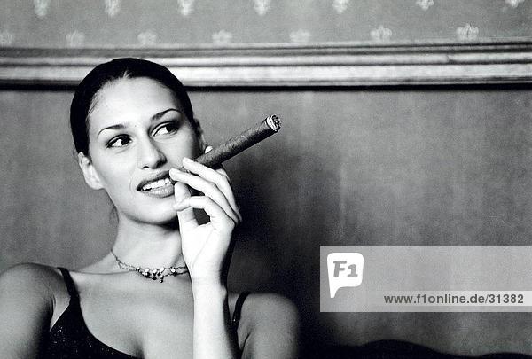 Nahaufnahme einer jungen Frau raucht eine Zigarre