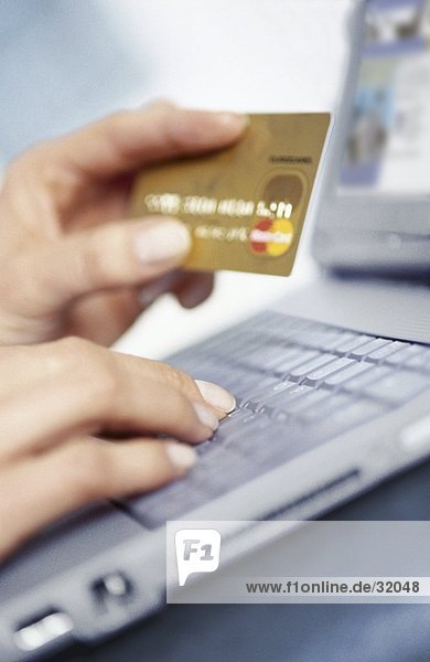 Frau hält eine Kreditkarte und benutze ein laptop