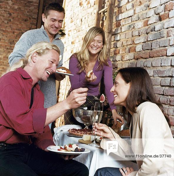 Young couple looking at a young man feeding a young woman