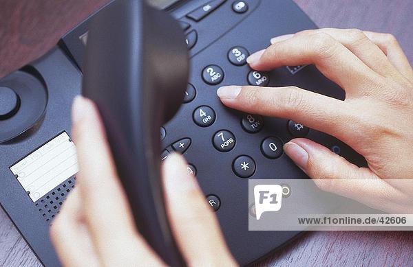 Close-up of woman's hands dialing landline phone