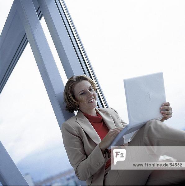 Geschäftsfrau mit Laptop auf einem Fensterbrett