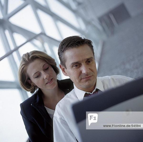 Businessman and businesswoman looking at laptop