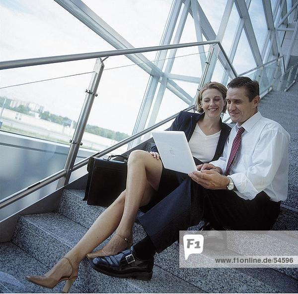 Businessman and businesswoman looking at laptop and smiling