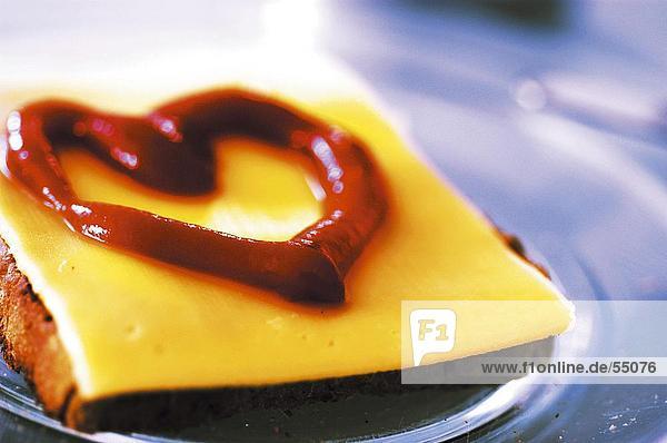 Close-up of toasted bread and cheese with heart shaped ketchup on plate