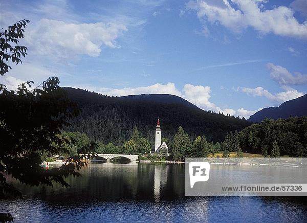 Brücke über einen Fluss führt zu einer Kirche Bohinj See Nationalpark Triglav Slowenien