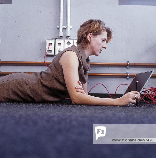 Seitenansicht geschäftsfrau auf dem Boden liegen und mit laptop