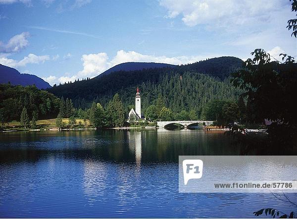 Bogenbrücke in der Nähe einer Kirche durch den Fluss Nationalpark Triglav See Bohinj Slowenien