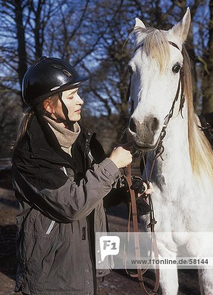 Seitenprofil of junge Frau hält Pferd mit rein