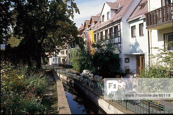 Tourists sitting besides canal in front of buildings  Eichsfeld  Lower Saxony  Germany