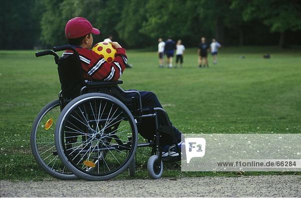 Behindertes Kind hält Soccer Ball im Rollstuhl