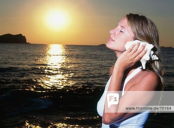 Young woman listening to shell