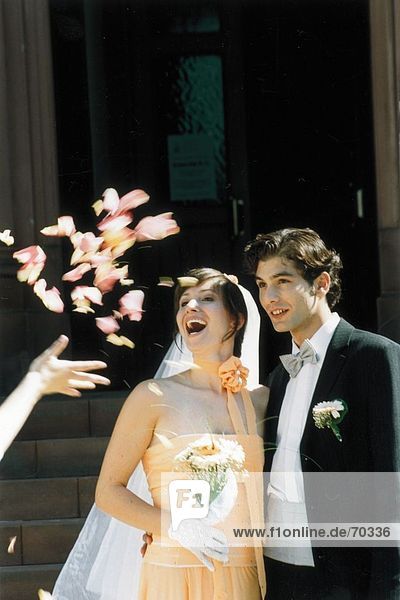 Person  die Hand werfen Blütenblätter auf frisch verheirateten paar