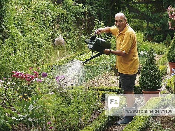 Seitenansicht Side älterer Mann bewässern Blumen im Garten