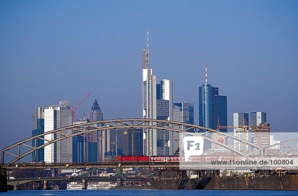 Train crossing bridge with city skyline in background  Frankfurt  Germany