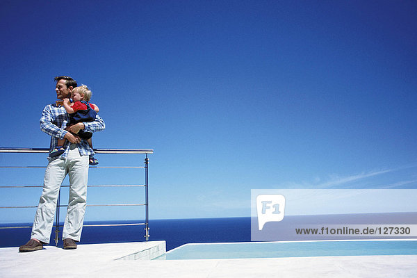 Father holding toddler while enjoying a view of the sea