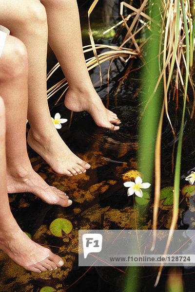 Frauen tauchen Füße in den Teich