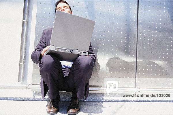 Geschäftsmann mit Computer in der Sonne sitzend