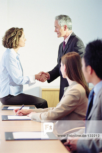 Businessman and businesswoman shaking hands in meeting