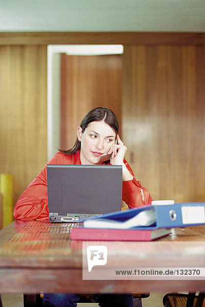 Woman using cell phone and laptop