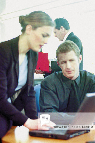 Businessman and businesswoman using laptop in office