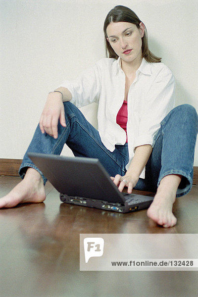Frau mit Laptop auf dem Boden sitzend