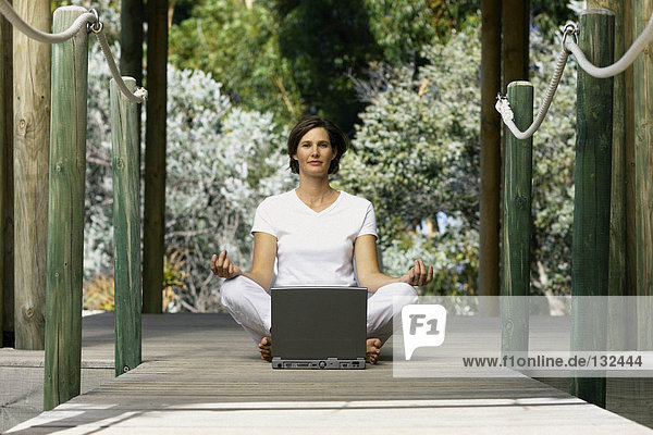 Frau mit Computer beim Yoga