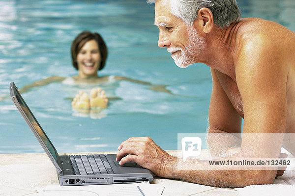 Mann und Frau im Schwimmbad mit Computer